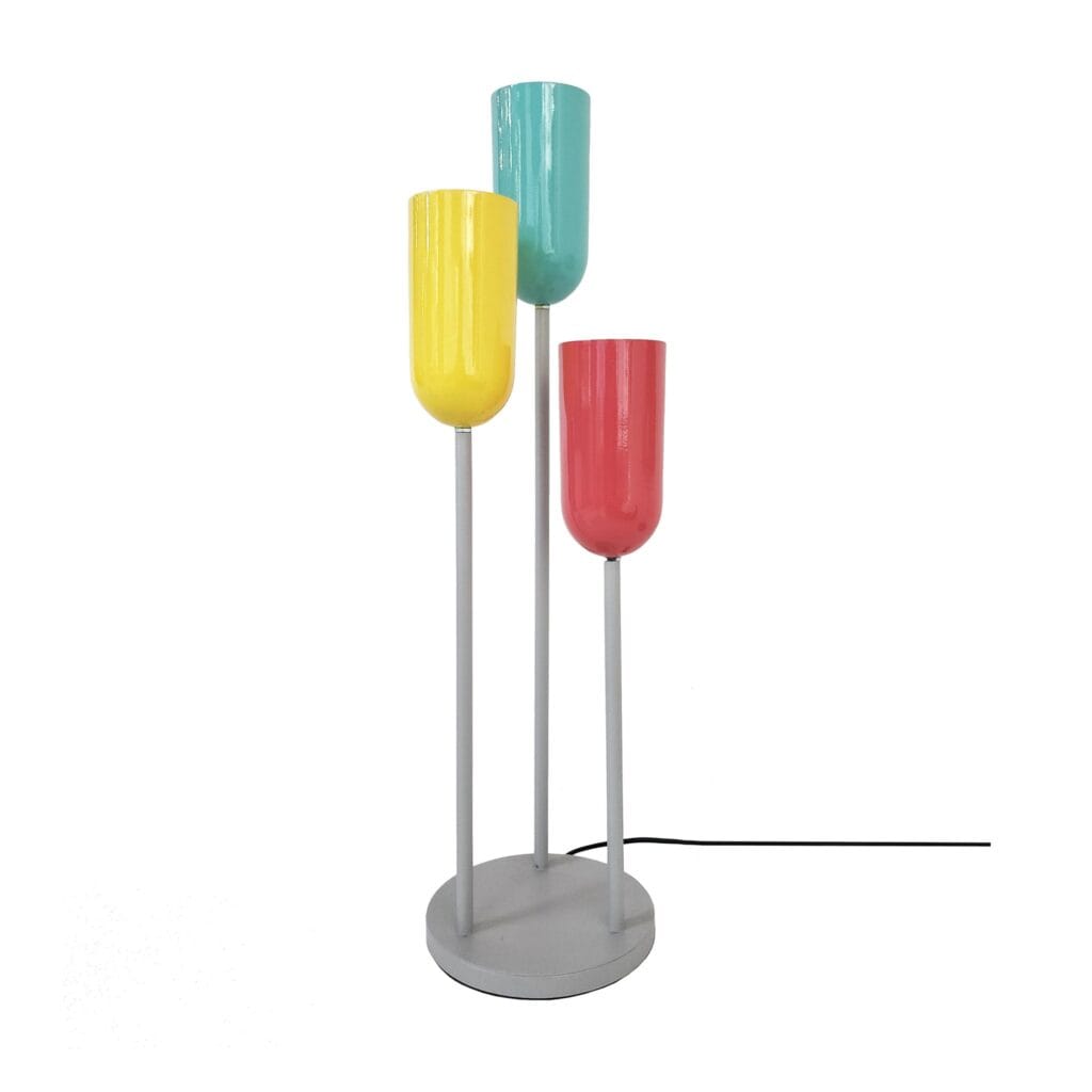 A fun and playful take on traditional lighting. Three mild steel rods with colourful lamp holder cups welded to a base plate. Dimensions Diameter : 190 mm Height : 520 mm Lamp Type : 3 x E27 Bulb excluded