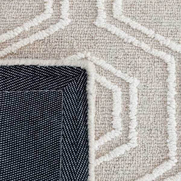 Handwoven in India this wool rug features a loop pile with a hexagon pattern and a durable cotton backing, offering a refined, texture finish. Earthy tones and subtle gradients mimic the colours and contours of mountainous landscapes, creating a grounding atmosphere in any room.
